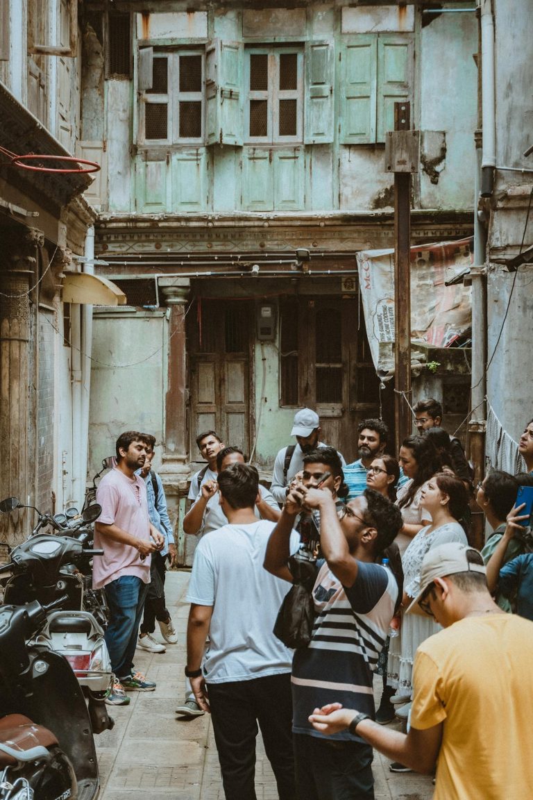 Tourists gathered in an old alleyway in Ahmedabad, India, learning about local history.